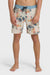Man wearing a pair of boardshorts that are primarily cream with a blue, coral, and yellow floral pattern and blue waistband on a white background.