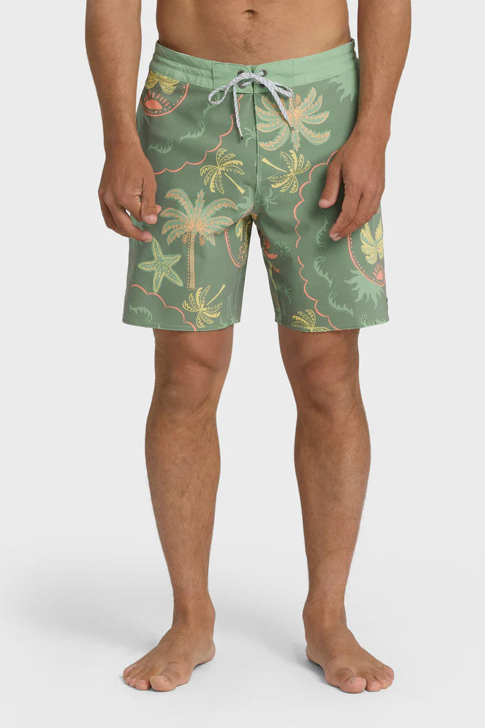 Man wearing a pair of boardshorts that are primarily green with a green, coral, and yellow palm tree and starfish design on a white background.