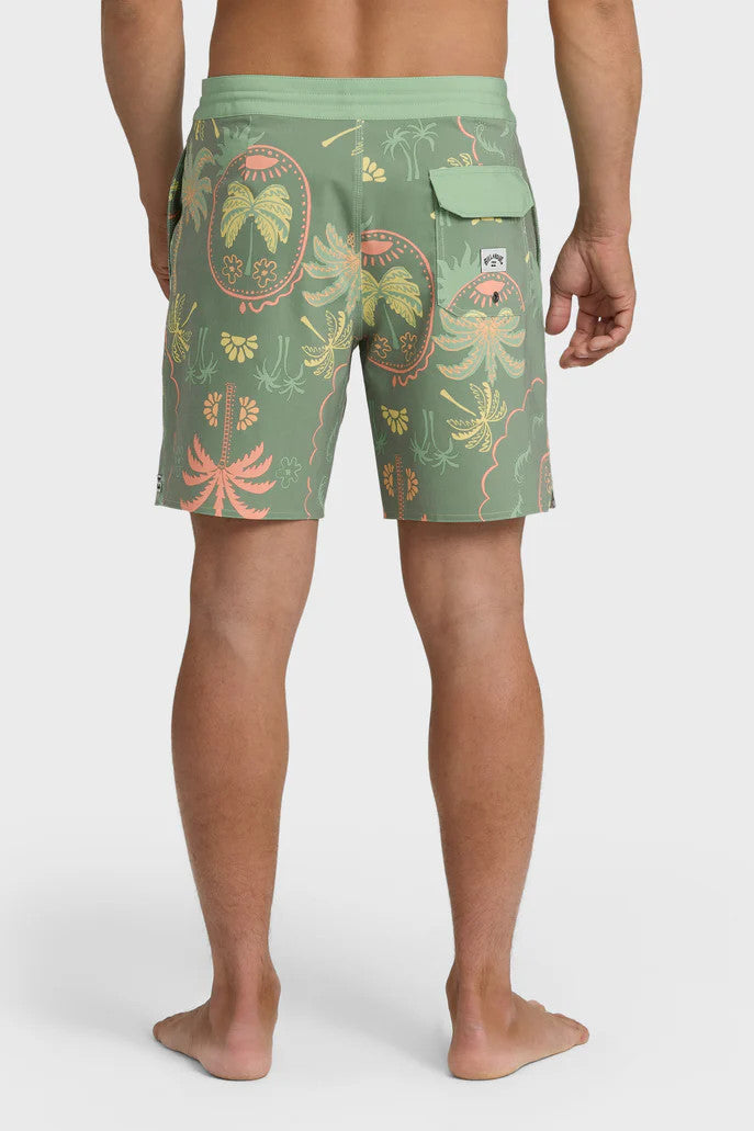 Back view of a man wearing a pair of boardshorts that are primarily green with a green, coral, and yellow palm tree and starfish design on a white background.