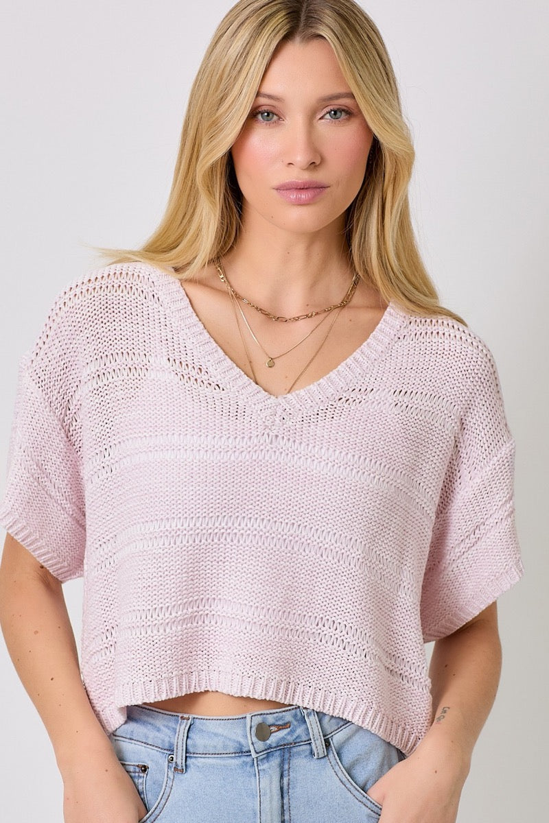 Woman wearing a lavender sweater and light blue denim skirt on a white background