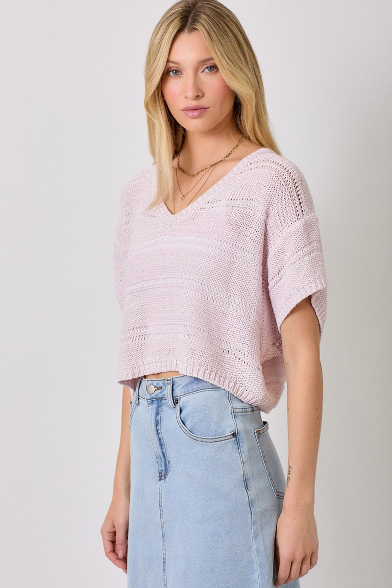 Woman wearing a lavender sweater and light blue denim skirt on a white background