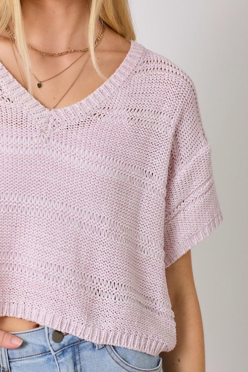 Detail view of a woman wearing a lavender sweater and light blue denim skirt on a white background