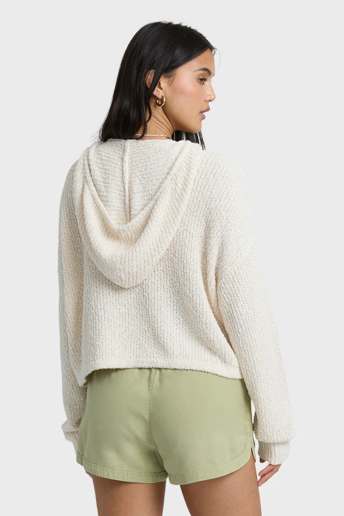 Woman wearing a white knit hoodie and light green shorts on a white background