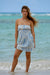 Woman in a strapless dress standing on a beach with ocean in the background