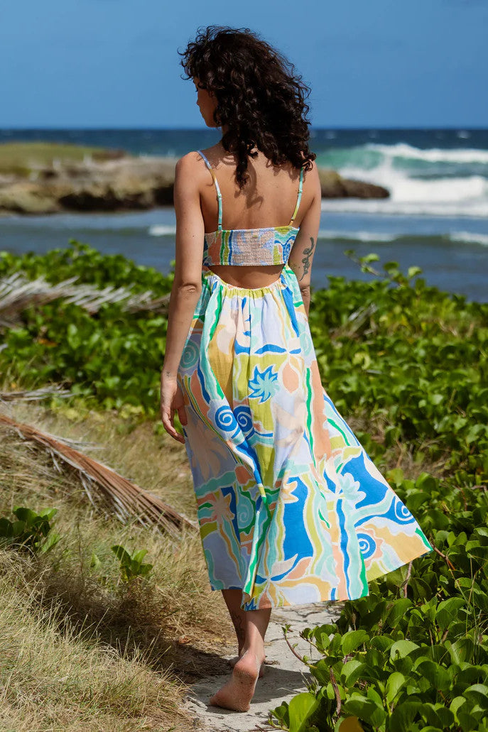 Woman in a colorful dress walking along a path by the ocean.