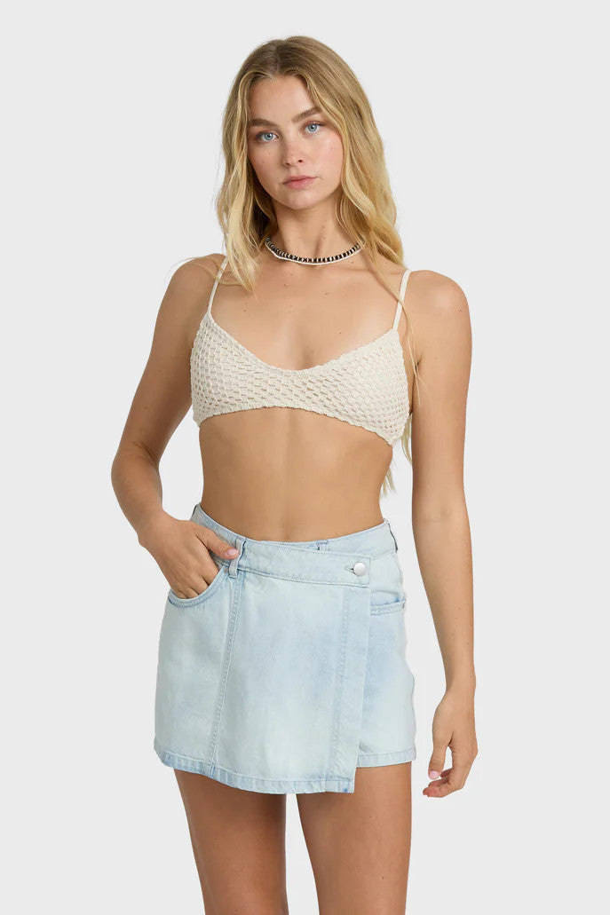 Woman wearing a textured bralette and denim skort on white background
