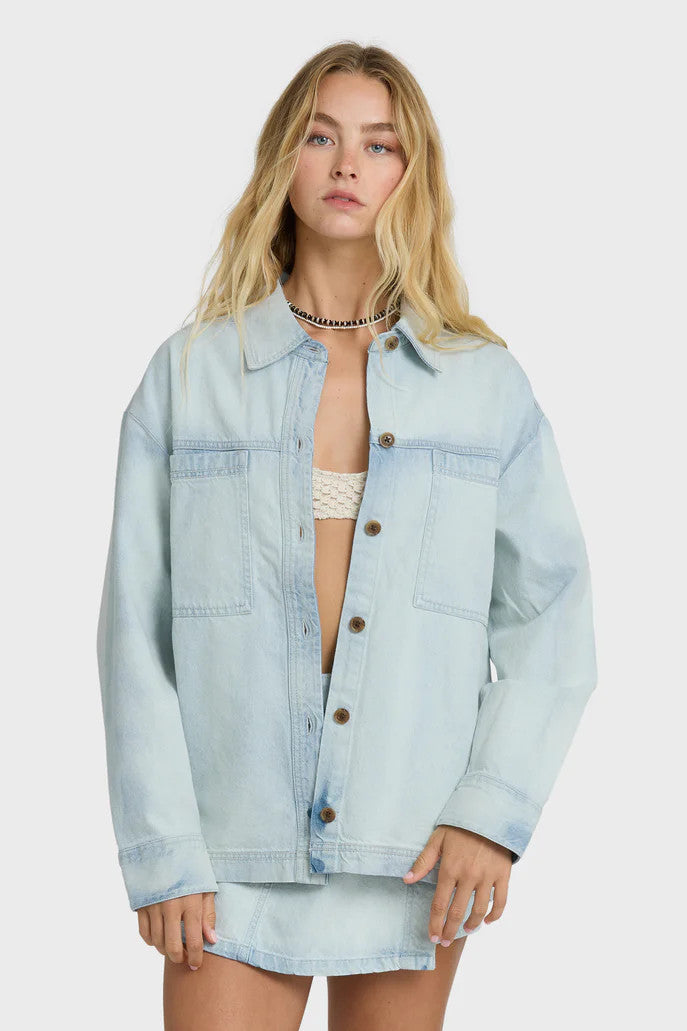 Woman wearing a light blue denim shirt over a bikini on a white background