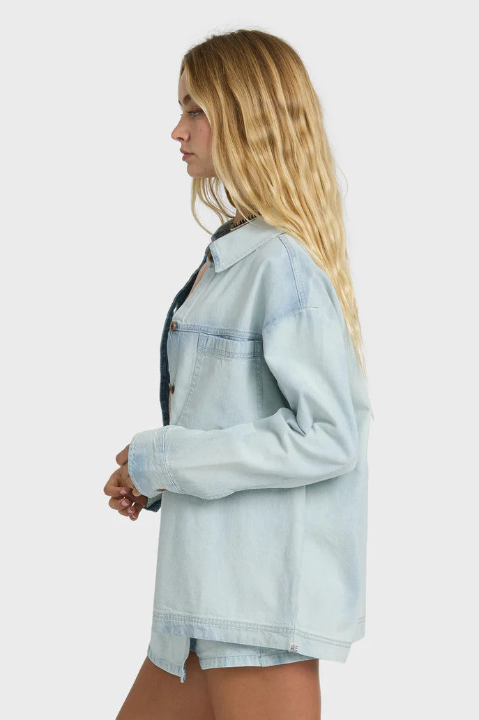 Woman wearing a light blue denim shirt over a bikini on a white background