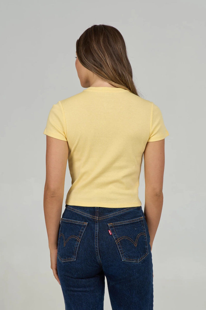 Woman wearing a yellow t-shirt and blue jeans on a gray background