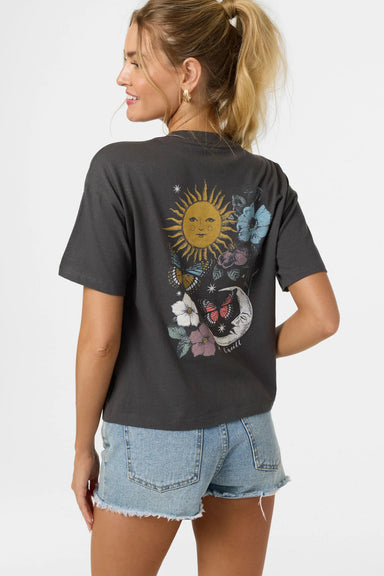 Woman wearing a black t-shirt with a colorful graphic design on the back, standing against a plain background.