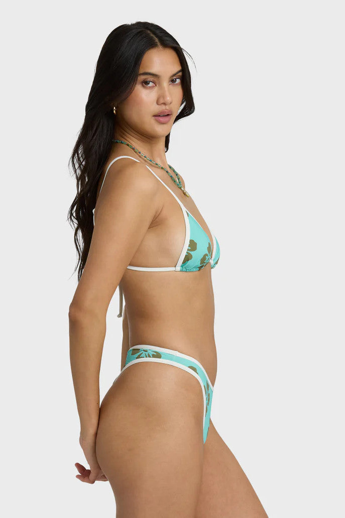 Woman wearing a turquoise bikini with floral patterns on a white background