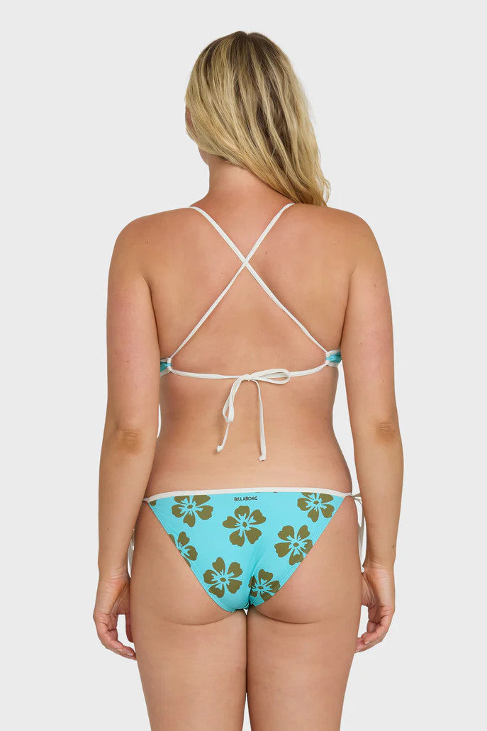Back view of a woman wearing a blue bikini with floral patterns on a white background