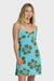 Woman wearing a blue dress with green floral patterns on a white background