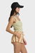 Woman wearing a light green tank top and striped shorts with a black cap on a white background