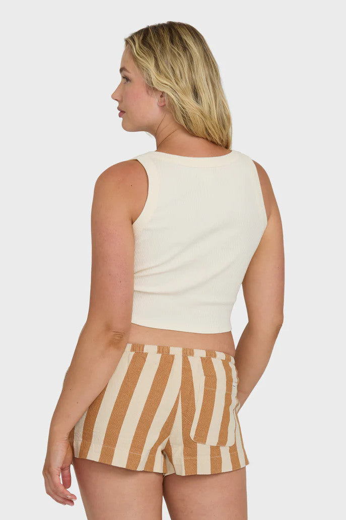 Woman wearing a white sleeveless top and striped shorts on a plain background