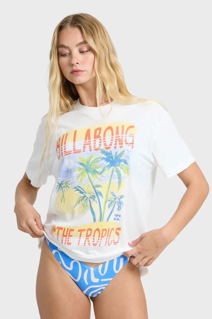 Woman wearing a Billabong t-shirt with palm tree graphic and blue bikini bottoms against a white background