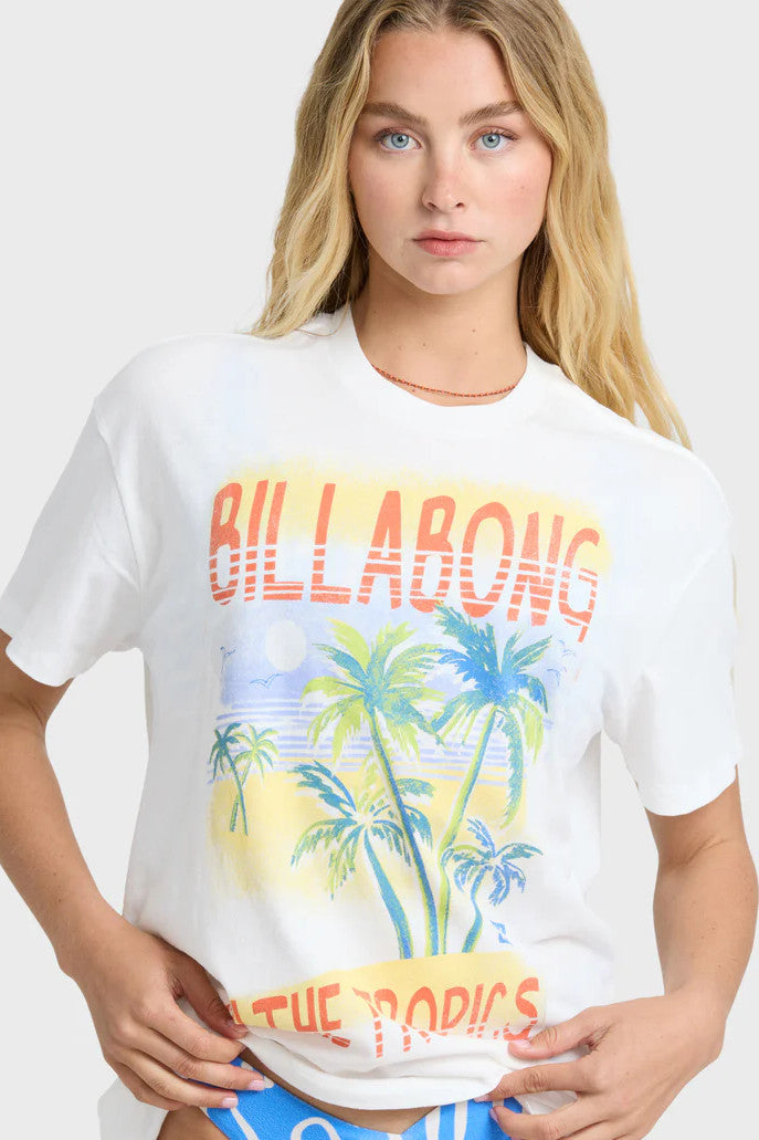 Woman wearing a Billabong t-shirt with palm tree graphic and blue bikini bottoms against a white background
