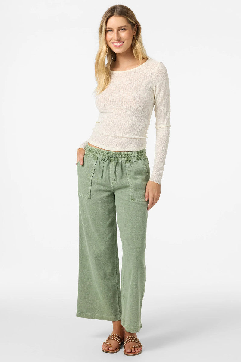 Woman wearing a white sweater and green pants on a white background