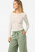 Woman wearing a white sweater and green pants on a white background
