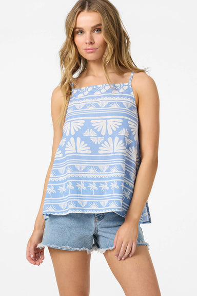 Woman wearing a blue and white patterned sleeveless top with denim shorts on a white background