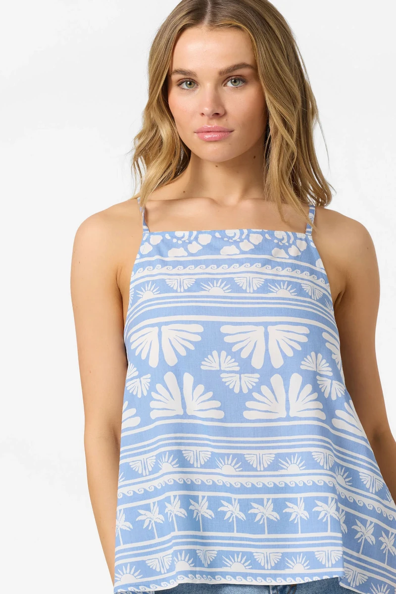 Woman wearing a blue and white patterned sleeveless top against a white background