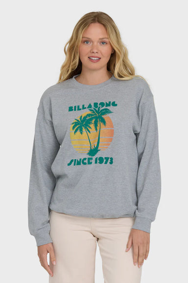 Woman wearing a gray sweatshirt with a palm tree design and 'Billabong Since 1973' text on a white background