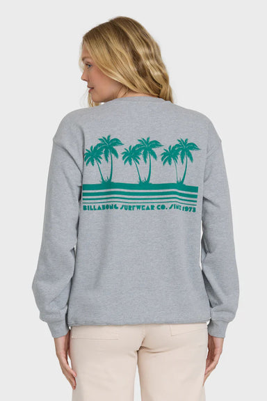 Back view of a woman wearing a gray sweatshirt with a palm tree design and "billabong surfwear co since 1973" text on a white background