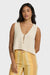 Woman wearing a beige knit tank with yellow striped pants on a white background