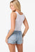 Woman wearing a white tank top and denim shorts on a white background