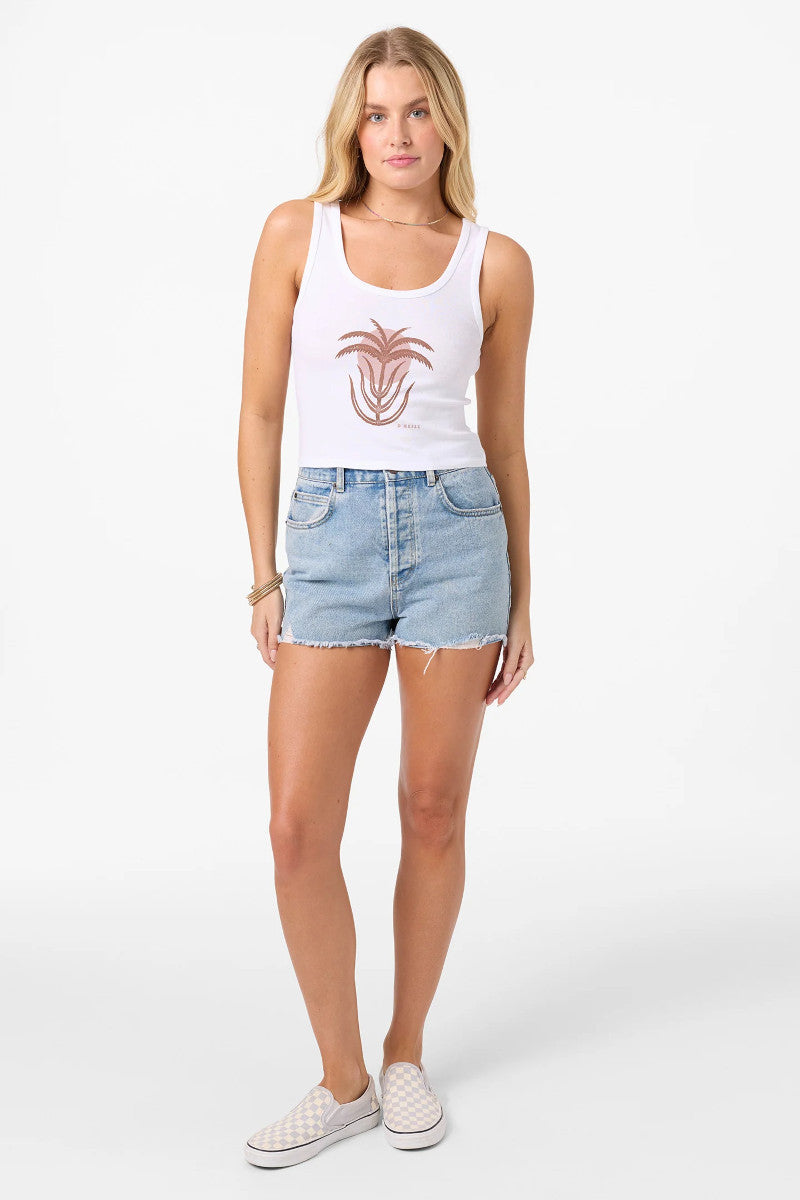 Woman wearing a white tank top with a palm tree design and denim shorts on a white background