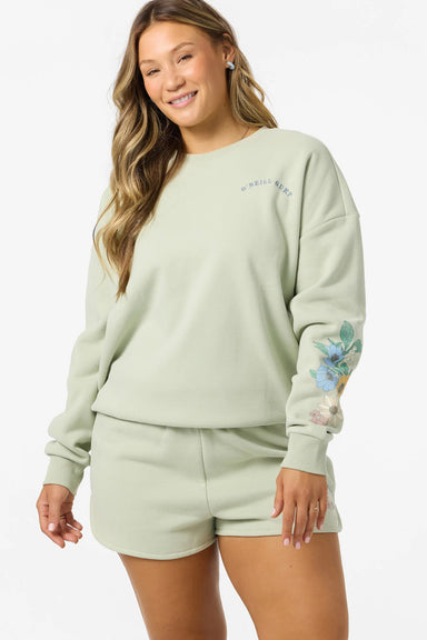 Woman wearing a light green sweatshirt and shorts set with floral designs on a white background