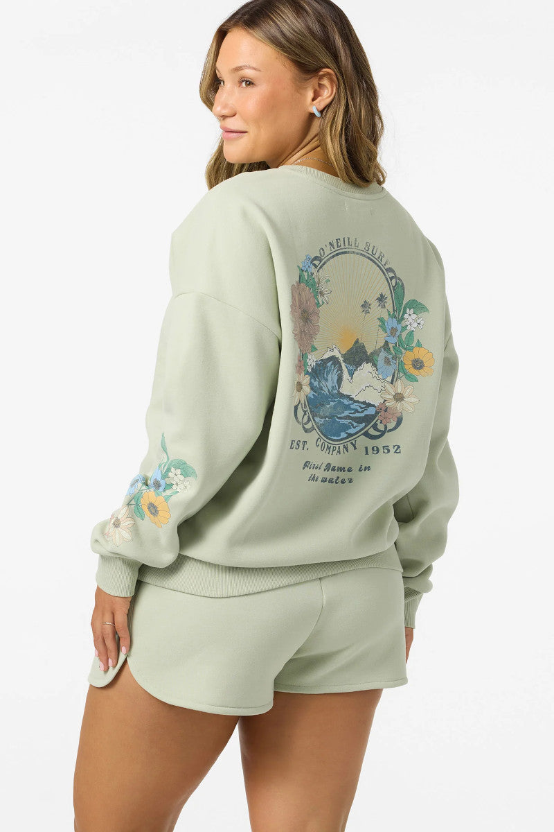 Woman wearing a light green sweatshirt with a floral design on the back, standing against a white background.