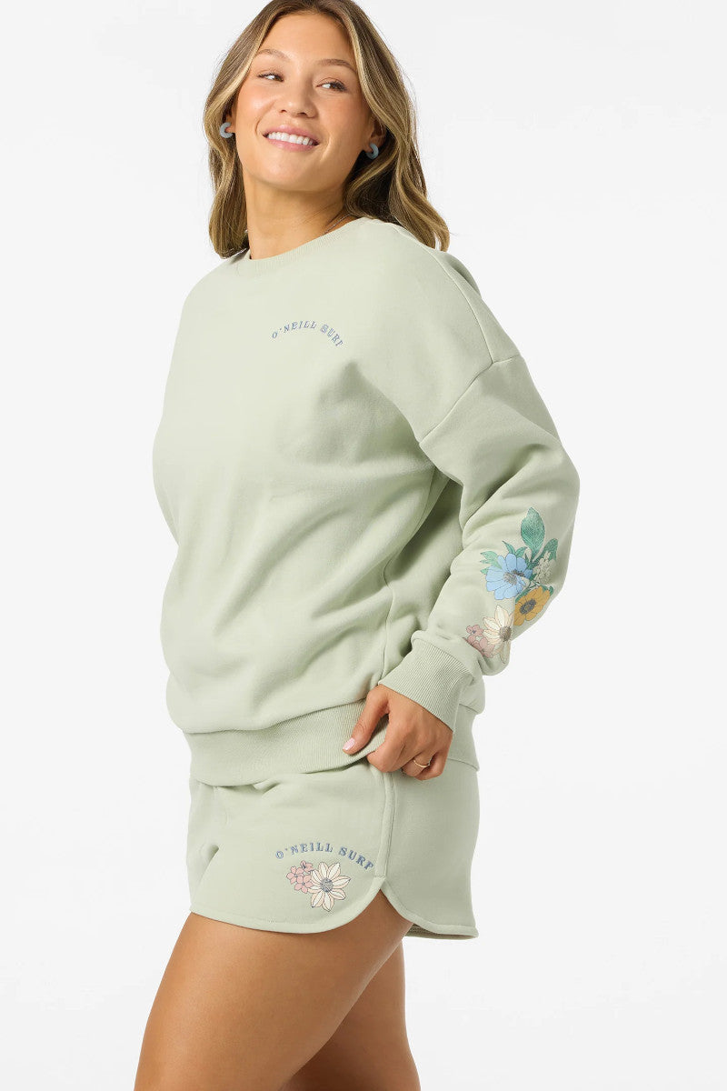 Woman wearing a light green sweatshirt and skirt with floral designs on a white background