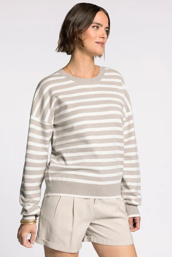 Woman wearing a striped sweater and beige shorts on a white background