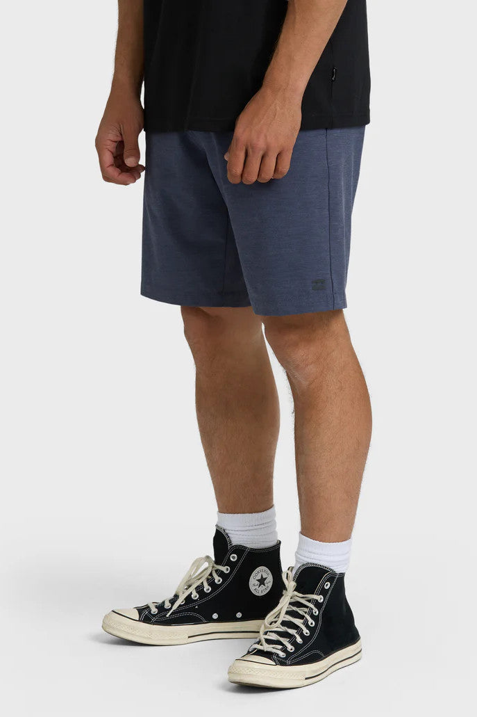Person wearing navy shorts and black Converse shoes on a white background