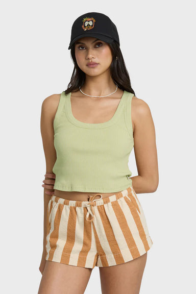 Woman wearing a green tank top and striped shorts with a black cap on a white background