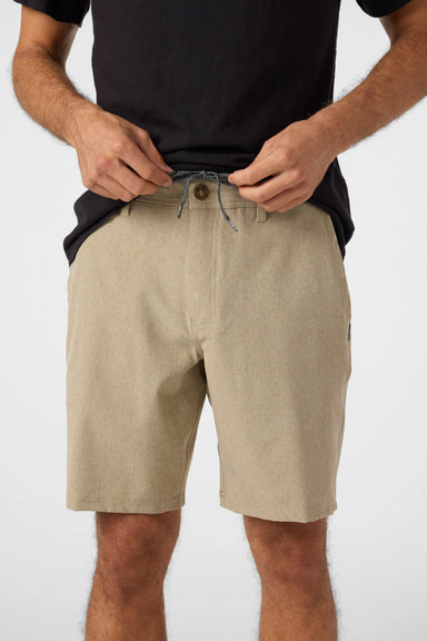Person wearing beige shorts and a black shirt on a white background