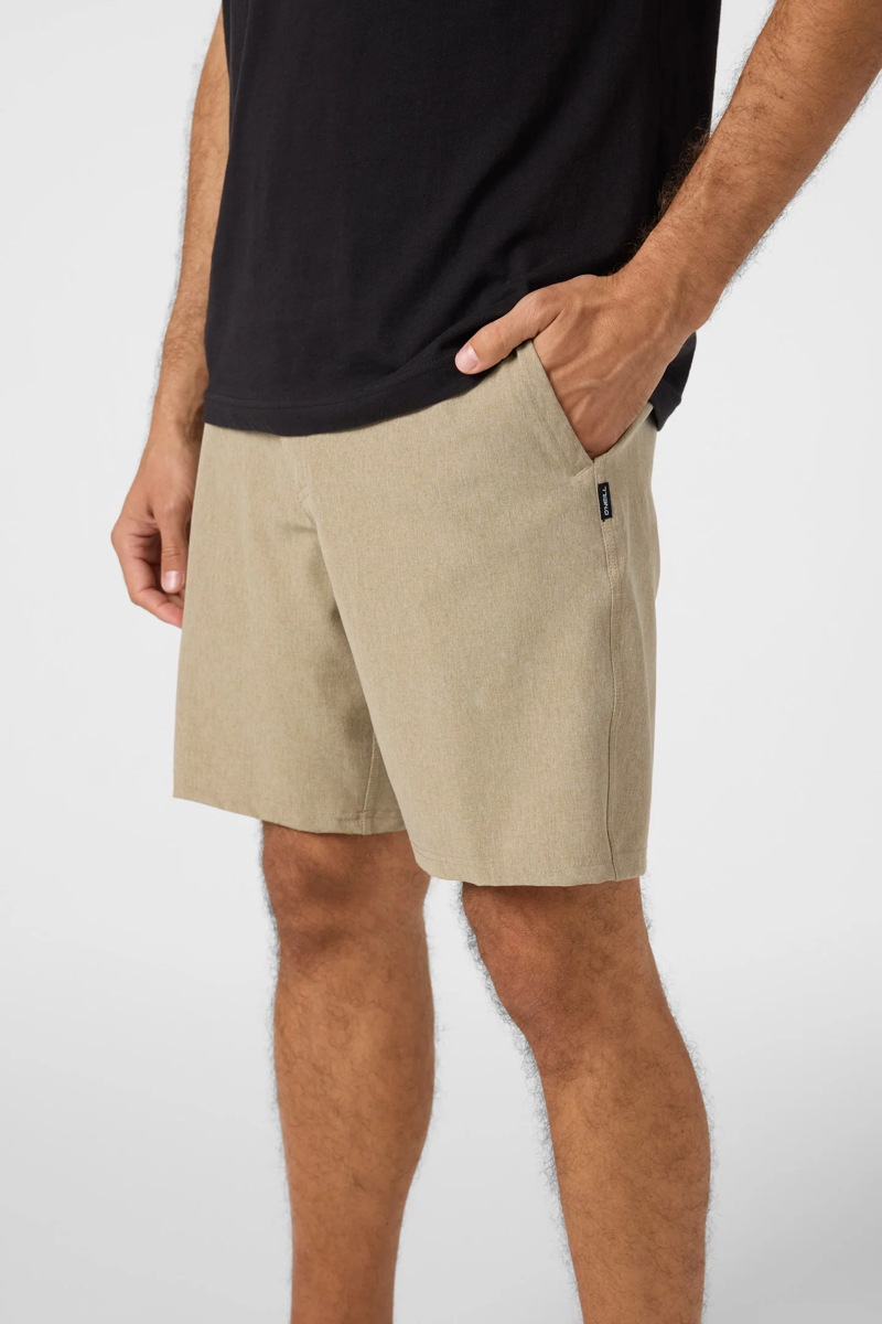 Person wearing beige shorts and a black shirt on a white background