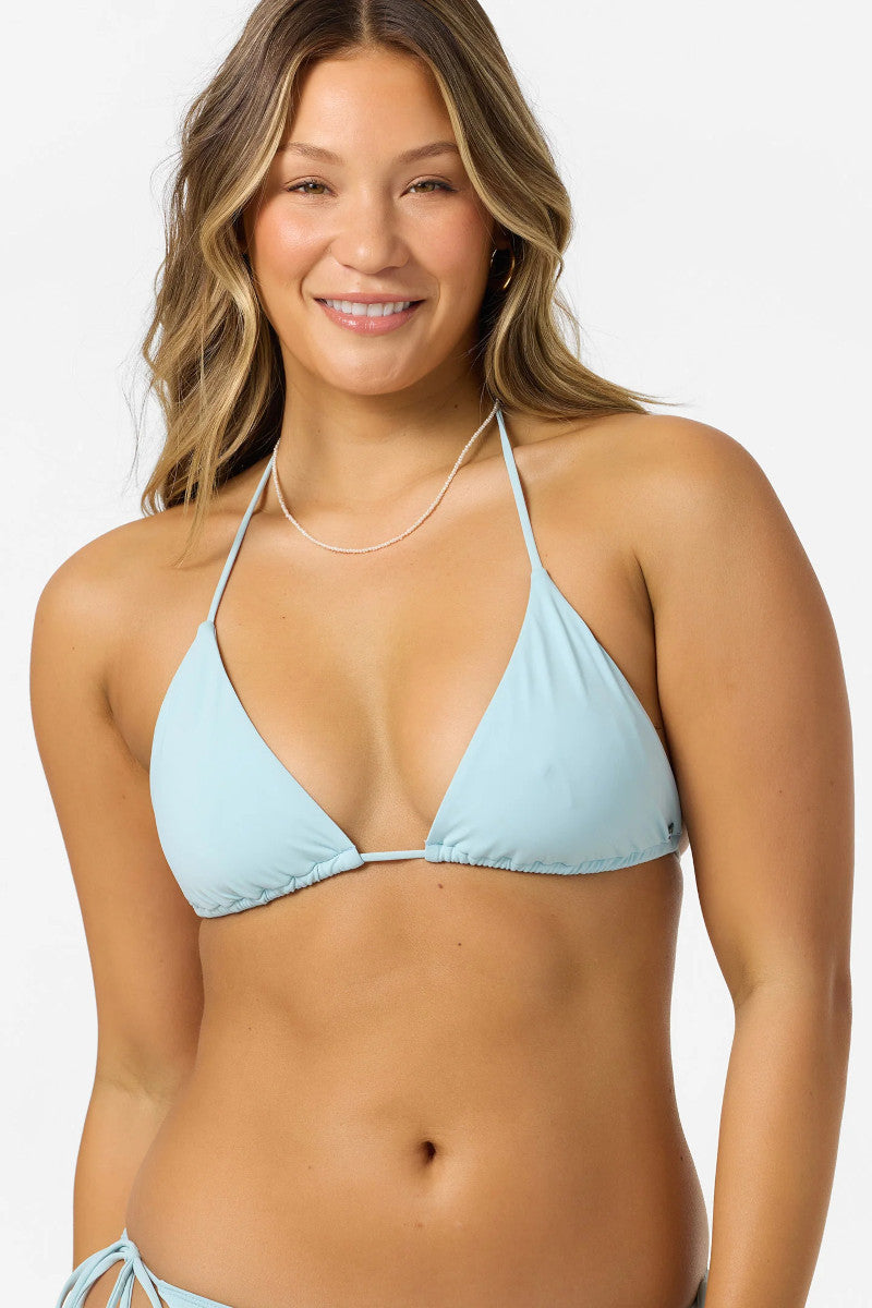 Woman wearing a light blue triangle bikini top on a white background