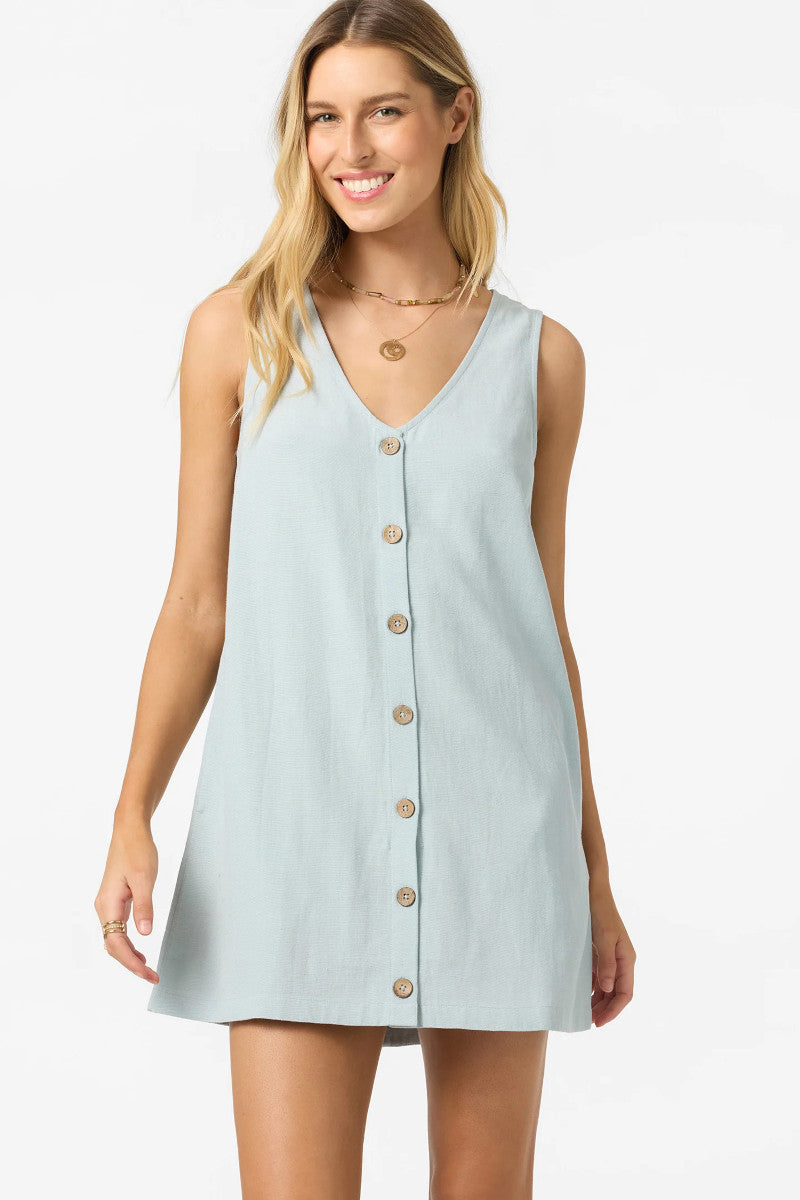 Woman wearing a light blue sleeveless dress with buttons on a white background