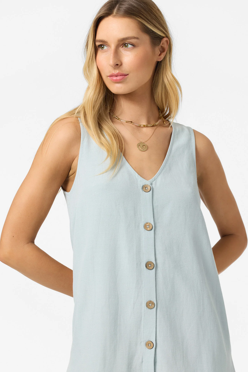 Woman wearing a light blue sleeveless button-up dress on a white background