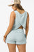 Woman wearing a light blue sleeveless top and shorts set on a white background