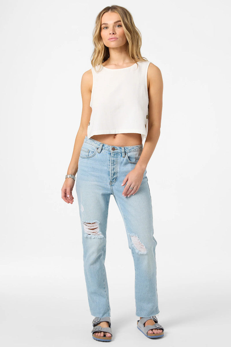 Woman wearing a white sleeveless top and light blue jeans on a white background