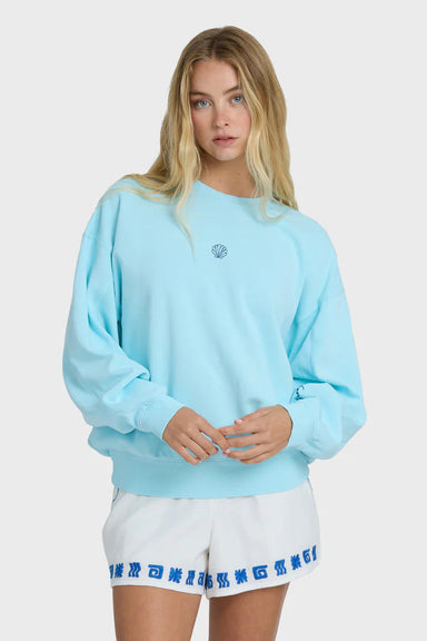 Woman wearing a light blue sweatshirt and white shorts with blue trim on a plain background