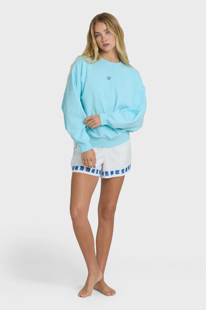 Woman wearing a light blue sweatshirt and white shorts with a blue trim on a white background