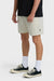 Man wearing beige shorts, black shirt, white socks, and black sneakers on a white background