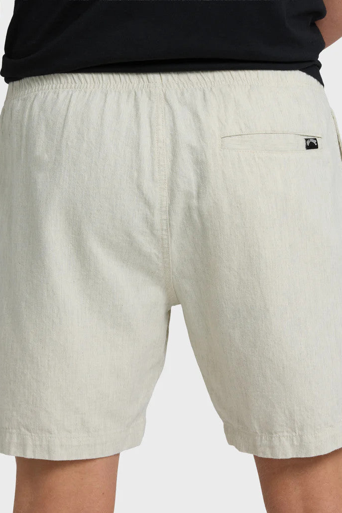 Close up of the back of beige shorts with a back pocket and brand logo