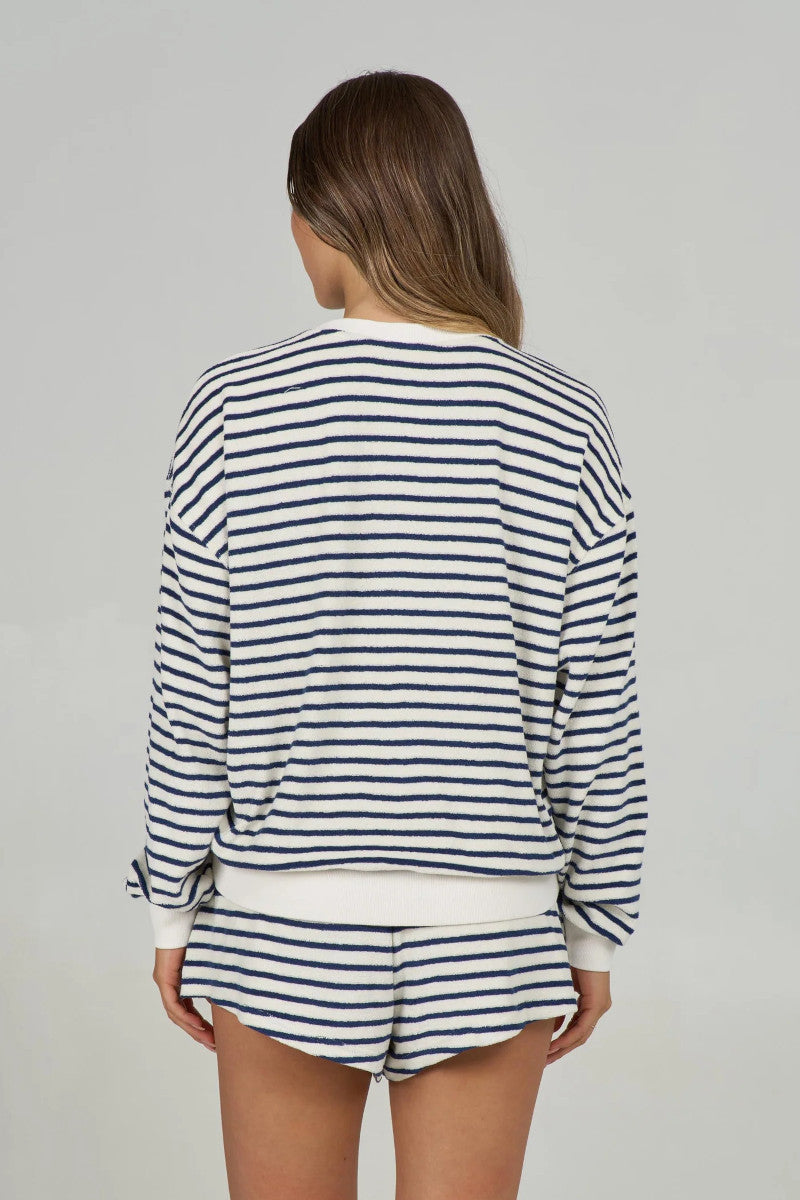 Back view of a woman wearing a striped sweatshorts and matching shorts on a gray background