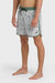 Man wearing gray swim trunks with a leaf pattern and contrasting green elastic waistband with drawstring on a white background