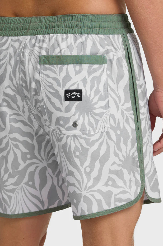 Man wearing gray swim trunks with a leaf pattern and contrasting green elastic waistband with drawstring on a white background